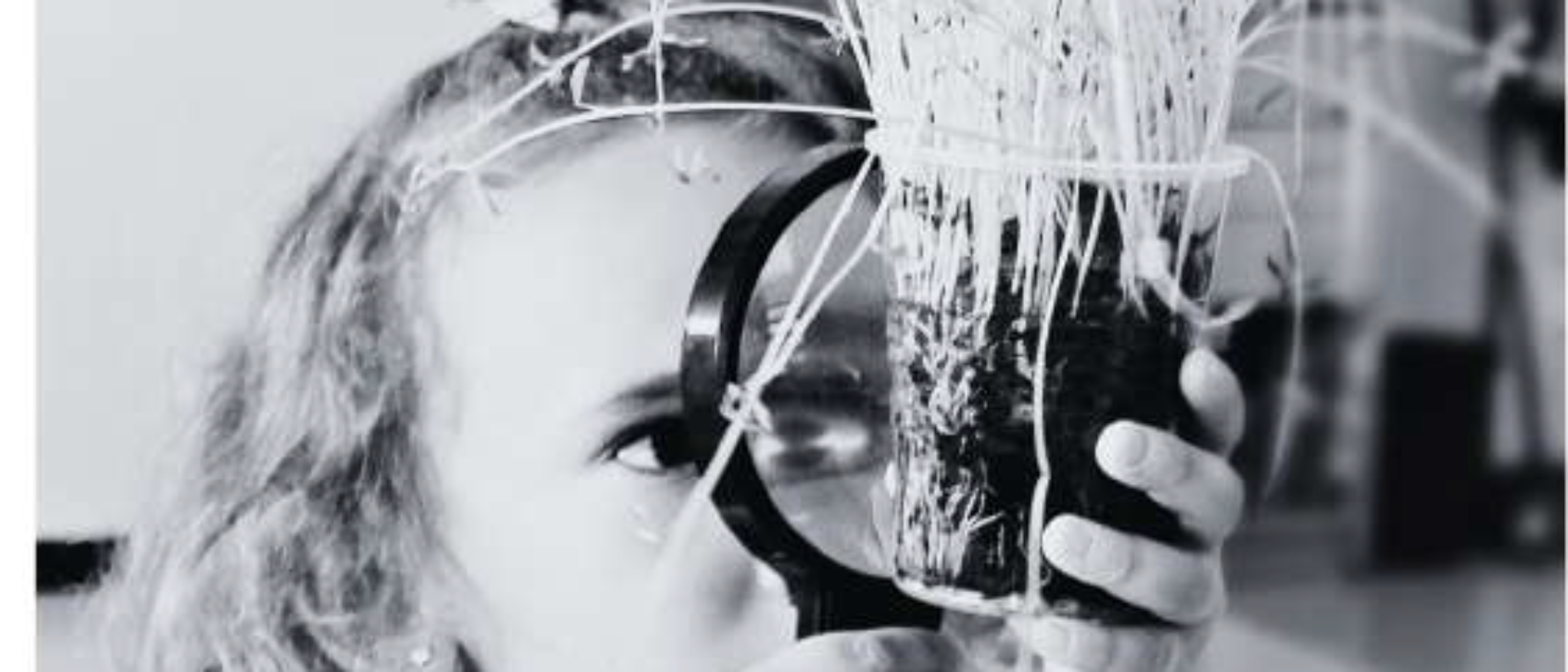 Imagen de alumna observando una planta con una lupa