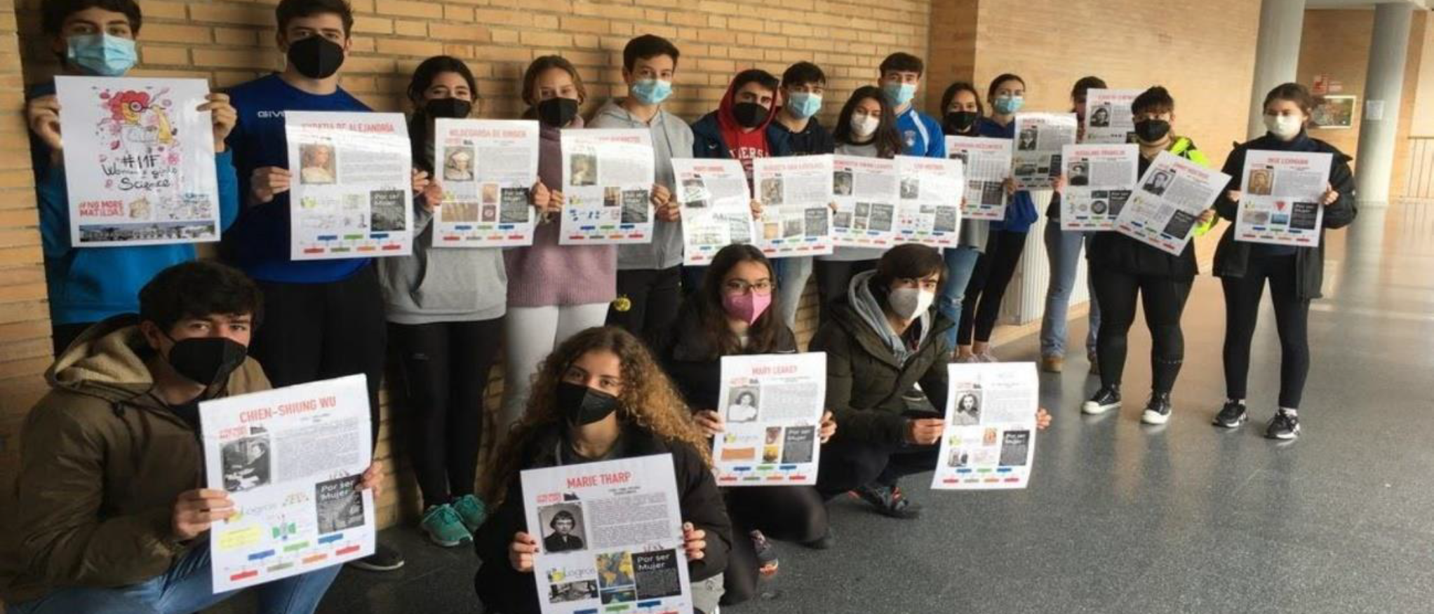 Alumnos con carteles para exposición permanente de mujeres científicas en los pasillos del centro